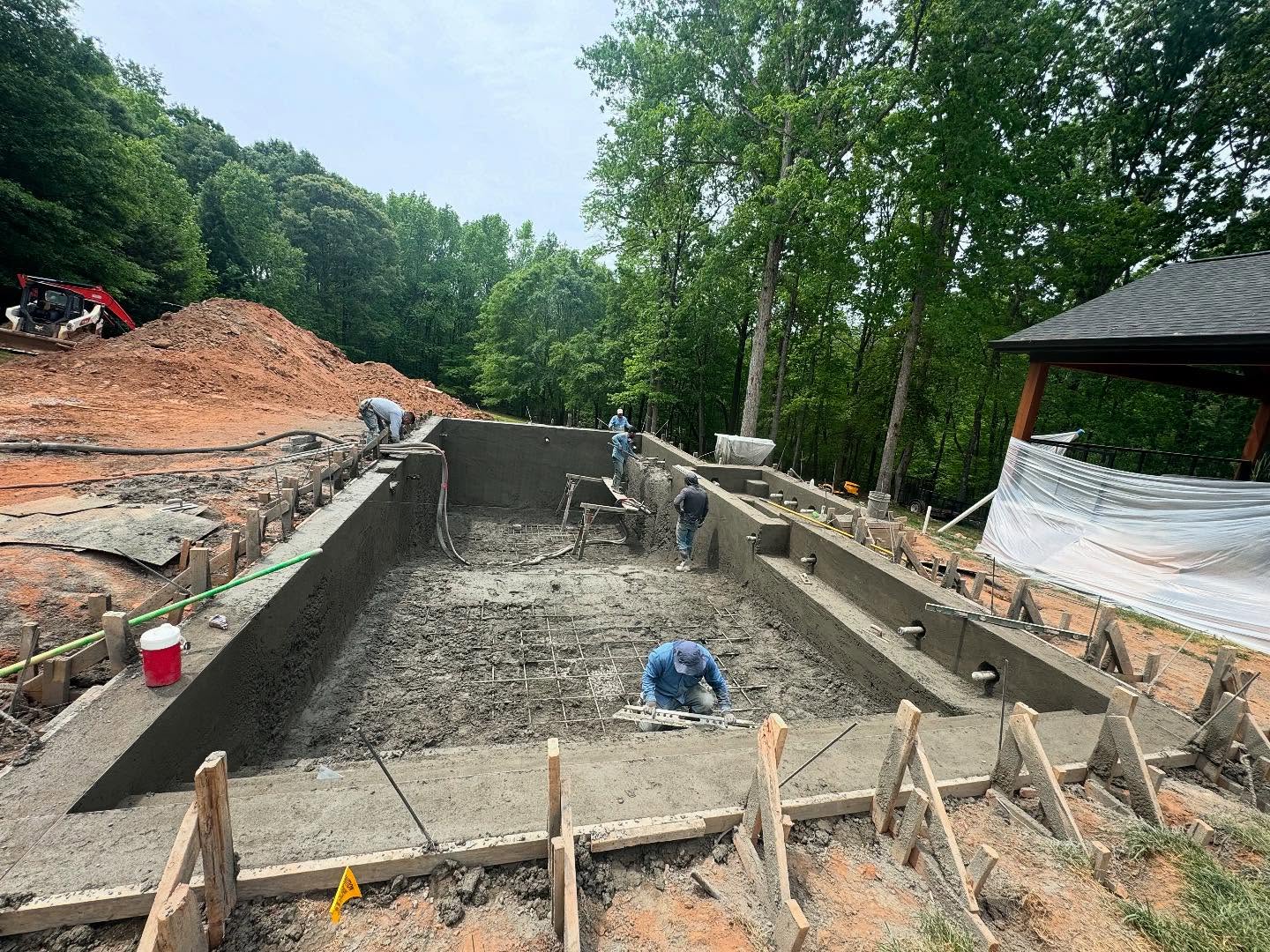 Crew applying shotcrete to gunite pool shell